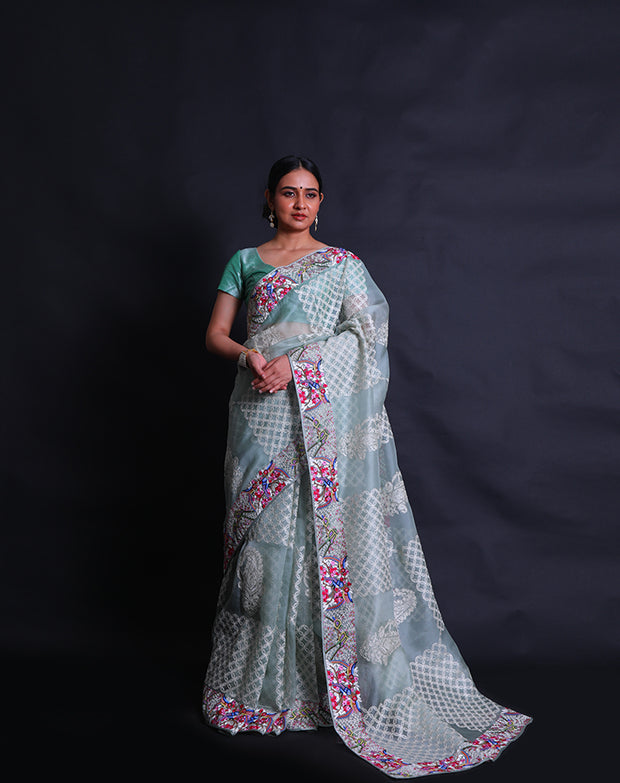 The light green organza saree you're describing is adorned with exquisite petit point embroidery in a modern design along the border,- EMB03360