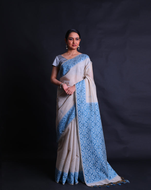 The Beige blended Tussar cotton saree with small buttis of zari and blue thread all over the drape,-  BLN01371