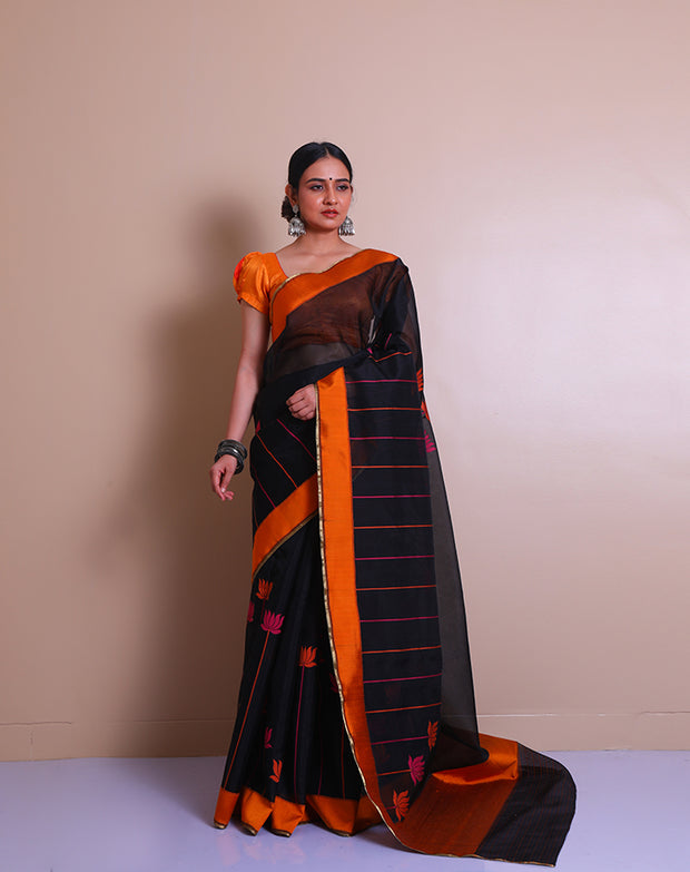 A black Banarasi cotton saree is beautifully adorned with colorful lines and a lotus design woven throughout the drape,- BSK04490