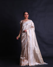 The beige tela zari Kota saree adorned with gold zari buttis all over the drape exudes classic elegance and sophistication.- KTJ04071
