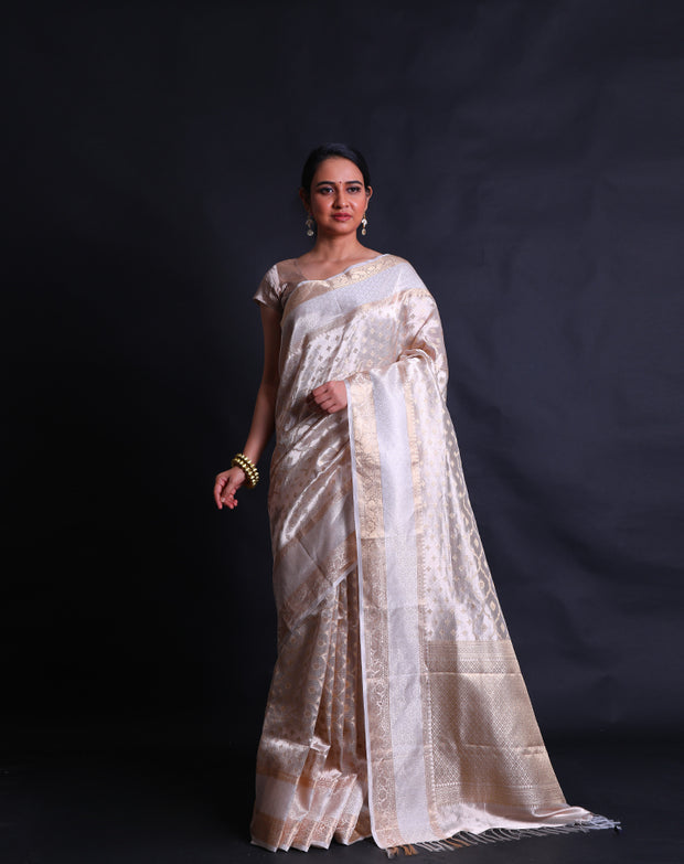 The beige tela zari Kota saree adorned with gold zari buttis all over the drape exudes classic elegance and sophistication.- KTJ04071