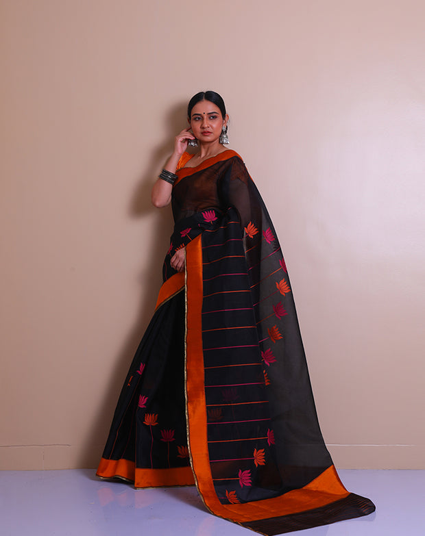 A black Banarasi cotton saree is beautifully adorned with colorful lines and a lotus design woven throughout the drape,- BSK04490