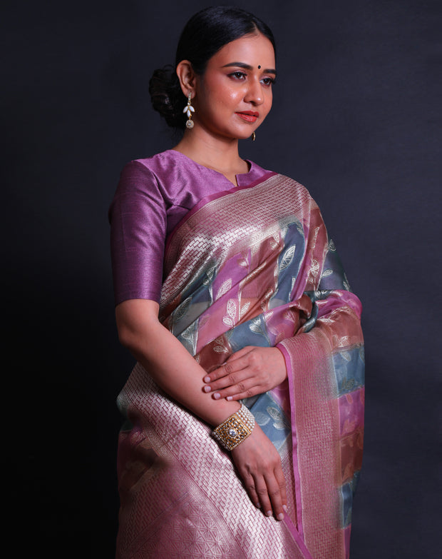 The pink Banarasi organza saree you're describing is a stunning piece, featuring multi-colored leaf designs in silver zari scattered across the drape. - BSK010622