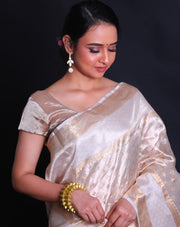 The beige tela zari Kota saree adorned with gold zari buttis all over the drape exudes classic elegance and sophistication.- KTJ04071