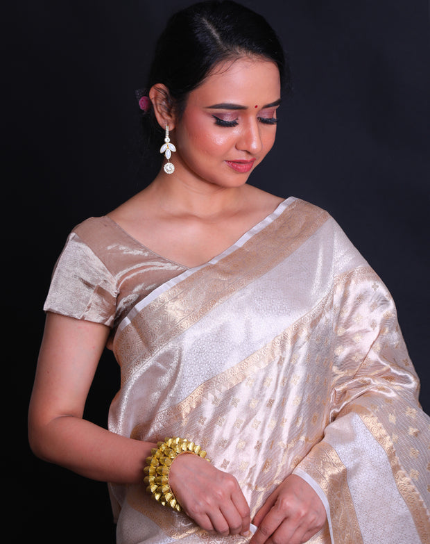 The beige tela zari Kota saree adorned with gold zari buttis all over the drape exudes classic elegance and sophistication.- KTJ04071